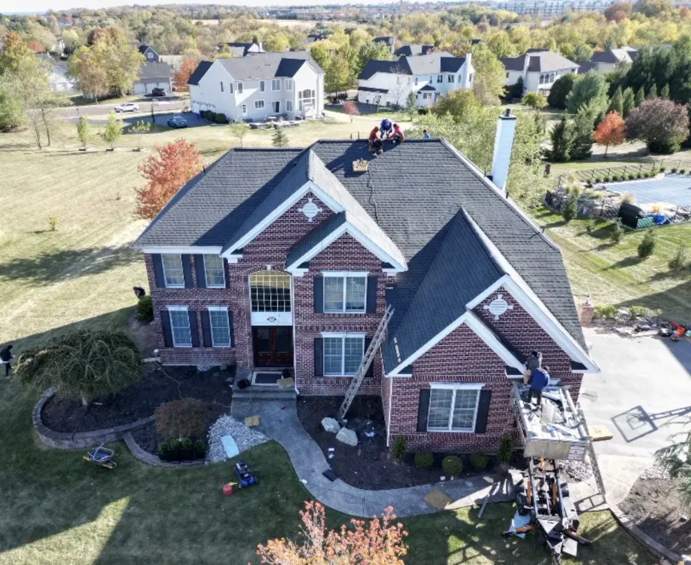 Roofing crew replacing the roof on a large brick colonial
